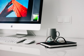 Imac on the table with glasses and copybook